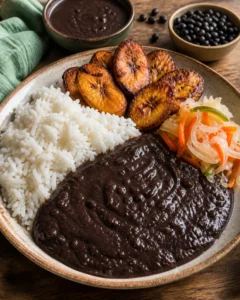 Pirinç, kızarmış plantain ve pikliz yanında servis edilen Haiti siyah fasulye sosu